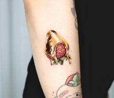 a person with a tattoo on their arm has a strawberry in the shape of a cow