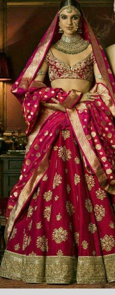 a woman in a red and gold bridal gown with her hands on her hips