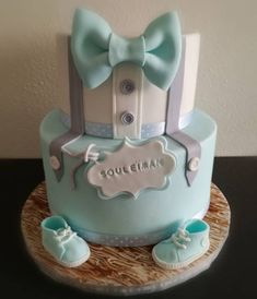 a blue cake with baby shoes on top and the name soulemar written on it