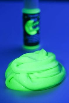 a bottle of neon green hair dye next to it's glower on a blue surface