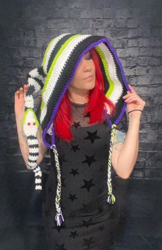 a woman with red hair wearing a multicolored crocheted hat and scarf