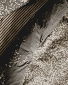 an unmade bed with striped pillows and floral bedspread on the bottom half