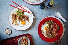 two plates with food on them and chopsticks next to one plate that has an egg in it