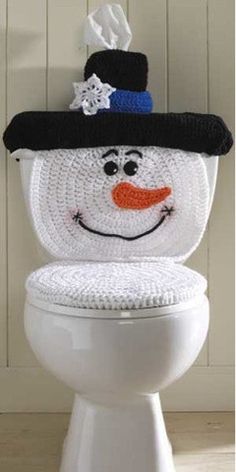 a white toilet with a snowman face on it's lid and a black hat