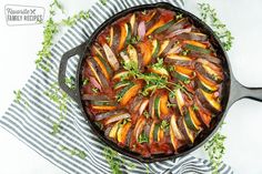 an iron skillet filled with vegetables on top of a blue and white striped towel