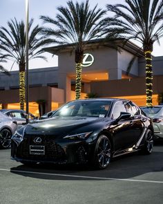 a black sports car parked in front of a building with palm trees and christmas lights