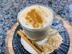 a cup of coffee with cinnamon and powder on a plate next to anisette