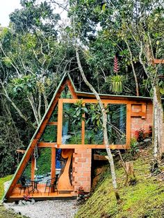 a small house built into the side of a hill surrounded by trees and shrubs, with a green roof