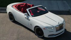 a white rolls royce parked in a parking lot with red seats on the back seat