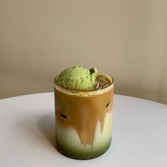 a cup filled with ice cream sitting on top of a white table next to a wall