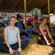 a group of people sitting on yoga mats in a tent with their backs turned to the side