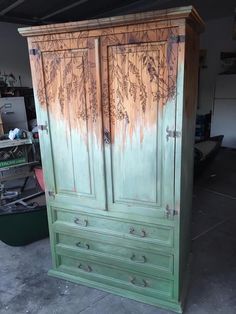 an old green armoire in a garage with graffiti on the doors and bottom part of it