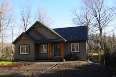 a house in the woods with lots of trees and dirt on the ground next to it