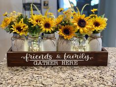 four mason jars with sunflowers are sitting on a counter