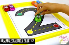 a child's hand is playing with a toy car on a number formation practice mat