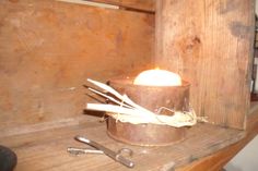 a candle is lit in an old bucket on a wooden shelf next to some tools