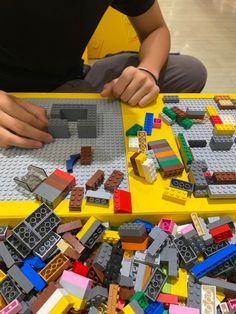 a person sitting at a table with legos all over the place and on top of it