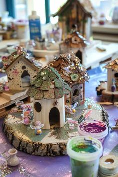 a table topped with lots of different types of birdhouses and other small houses on top of it