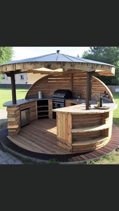 an outdoor kitchen is built into the side of a wooden structure with grill and sink