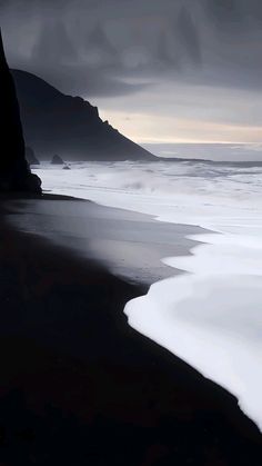 a black and white photo of the beach with waves coming in from the ocean,