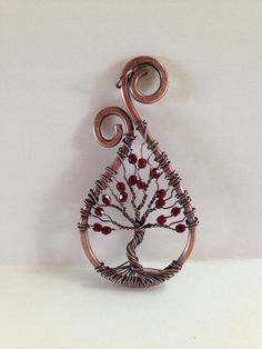 a wire tree with red berries hanging from it's side on a white wall