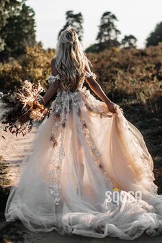 the back of a woman's dress with flowers on it, walking down a path