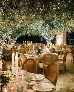 an outdoor dining area with tables, chairs and candles lit up at the end of each table