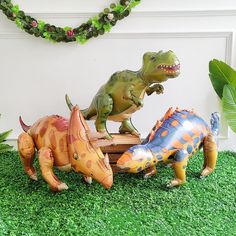 three plastic dinosaurs are standing in the grass