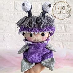 a small crocheted doll is wearing a purple outfit