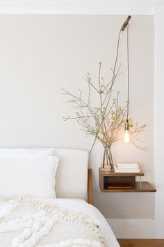 a bed with white linens and pillows in a bedroom next to a wall mounted lamp