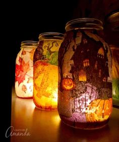 three jars with candles lit up in them on a table next to some pumpkins