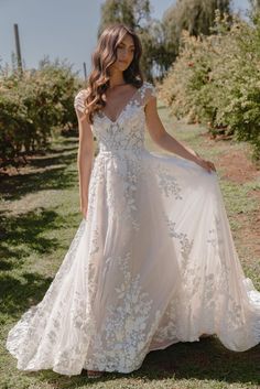 a woman in a wedding dress standing on the grass