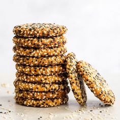 sesame seed cookies stacked on top of each other with seeds scattered around the edges and in between