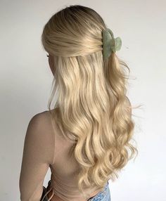 a woman with long blonde hair and a green bow in her hair is looking back at the camera