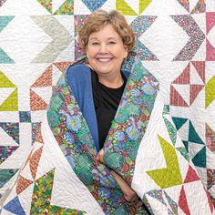 a woman standing in front of a quilt