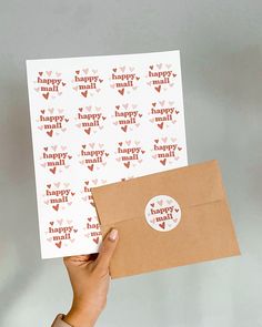 a person holding up two envelopes with stickers on them that say happy mail