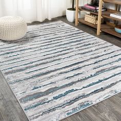 a white rug with blue and grey stripes on it in a living room area next to a window