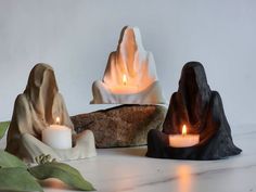 three candles sitting on top of rocks next to each other with one candle lit in the middle