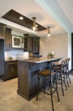 a kitchen with dark wood cabinets and marble counter tops is pictured in this image, there are four bar stools at the center of the island