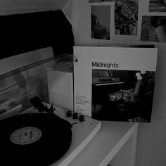 a record player sitting on top of a table next to a wall with pictures above it