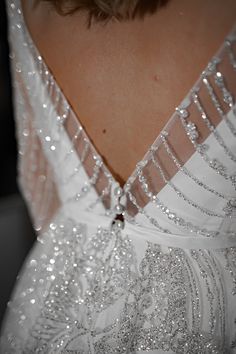 the back of a woman's wedding dress with sequins and beading