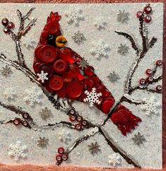 a red bird sitting on top of a tree branch covered in buttons and snowflakes