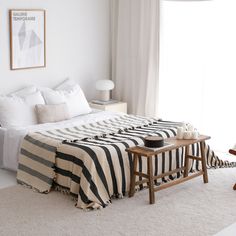 a bed with black and white striped bedspread in a bedroom next to a window