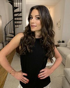 a woman standing in front of a staircase with her hands on her hips and looking at the camera