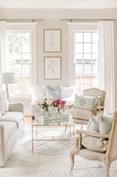 a living room filled with white furniture and lots of window sill space in front of two windows