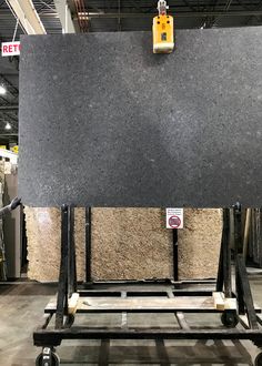 a large black granite slab on a dolly in a warehouse with other materials behind it