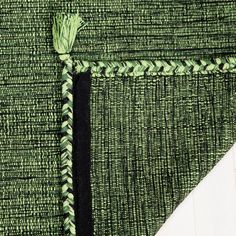 a piece of green and black woven material with a white triangle in the center, on top of it