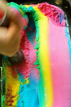 someone is painting a rainbow cake with white icing