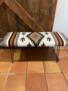 a bench sitting on top of a tiled floor next to a wooden door and wall