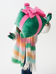 a person wearing a hat and scarf holding a large stuffed animal in the air with both hands